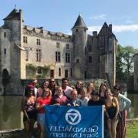 GVSU的学生在法国的一座城堡前举着GVSU的旗帜